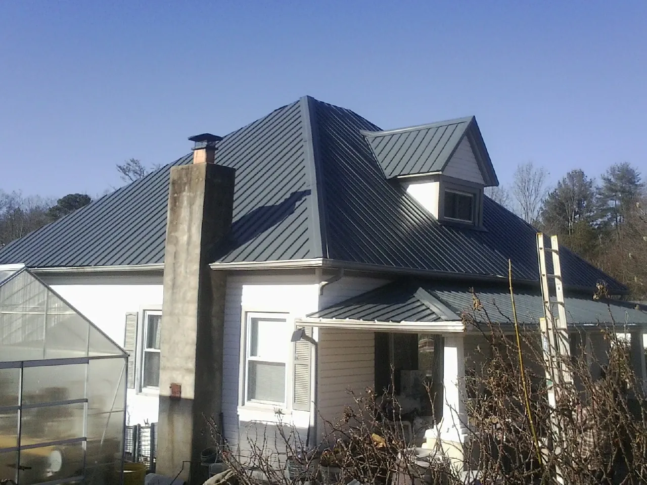 Dark blue standing seam metal roof on a white farmhouse with dormer — Slate & Tile Roof Repair by Roofing Brothers in Pompey