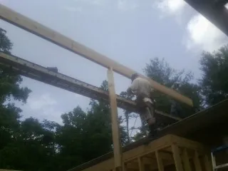 Carpenter setting a ridge beam over a new addition frame — Ice Dam Removal by Roofing Brothers in Pompey