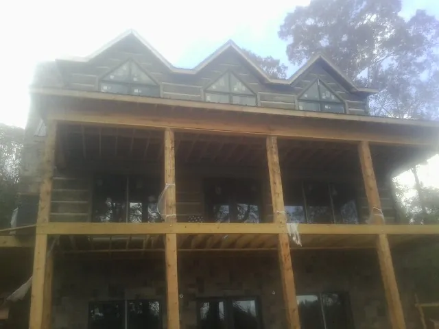 Dormers and porch framing on a large log home under construction — Roof Coating work by our crew in Pompey