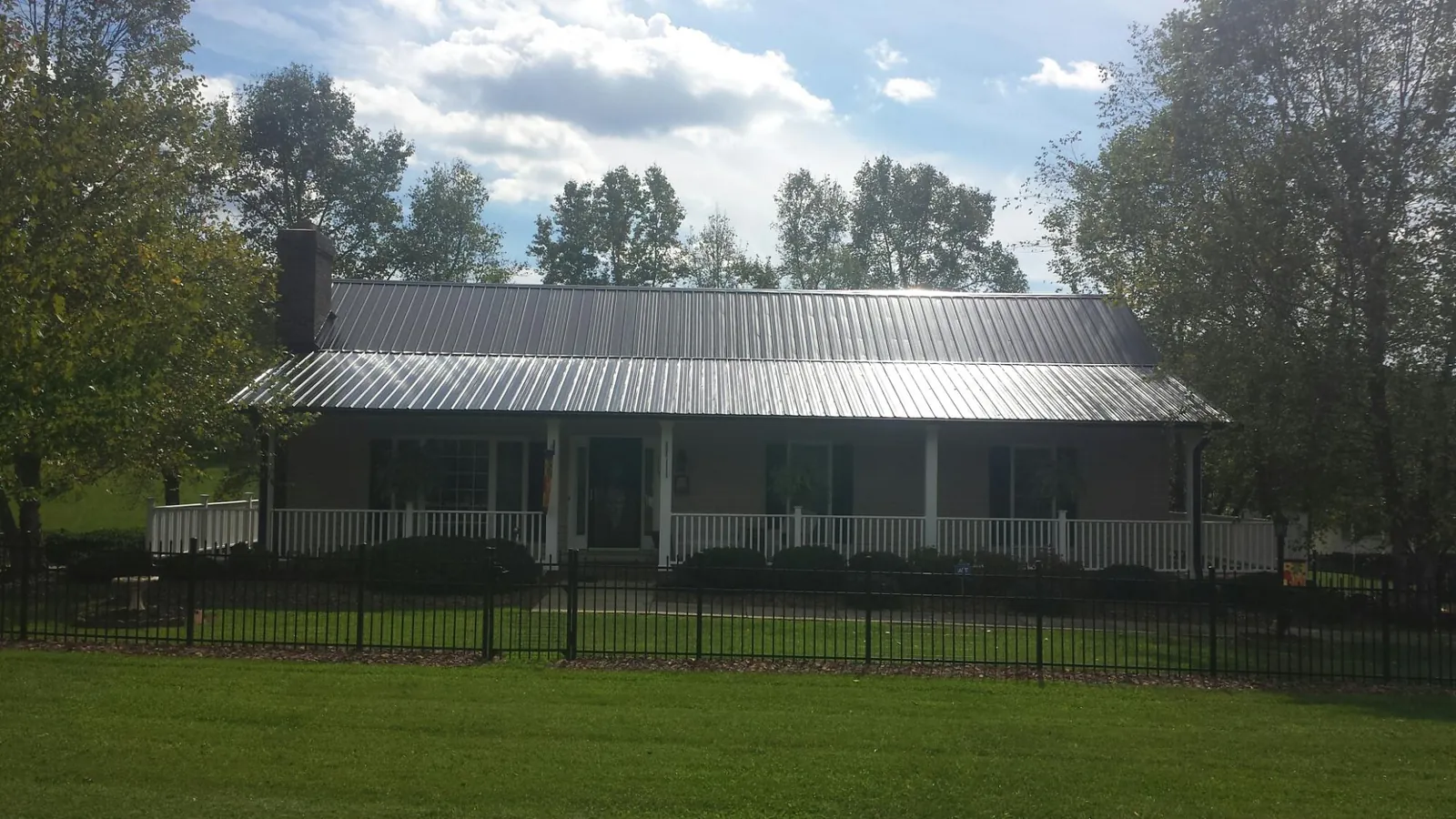 Gray metal roof on a brick ranch with a full width front porch — Gutter Guard Installation work by our crew in Pompey