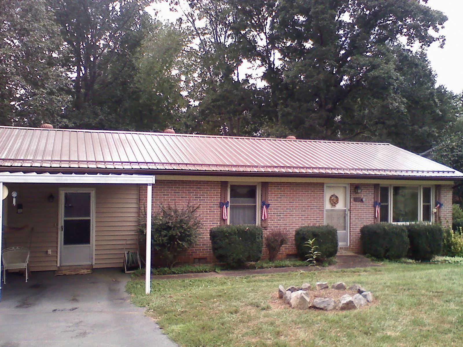 Bronze metal roof and carport on a brick ranch home — Roof Repair work by our crew in Pompey